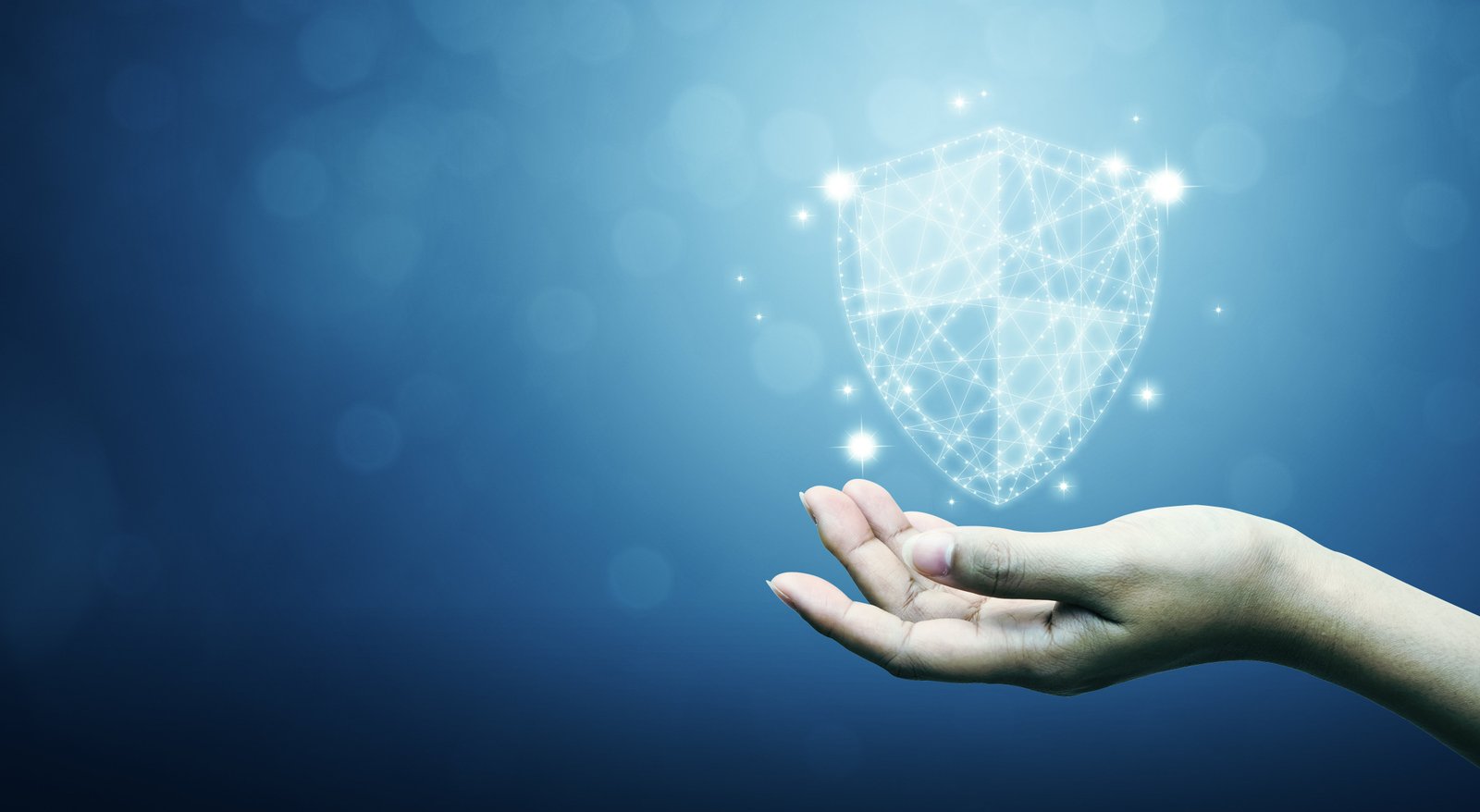 On a blue background, a white shield floats above a hand turned palm-up, symbolizing the MITRE ATT&CK® framework.